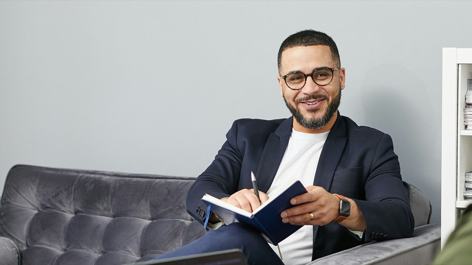 A man in a navy blazer and white tee, smiling with a direct gaze — reading high on both warmth and competence